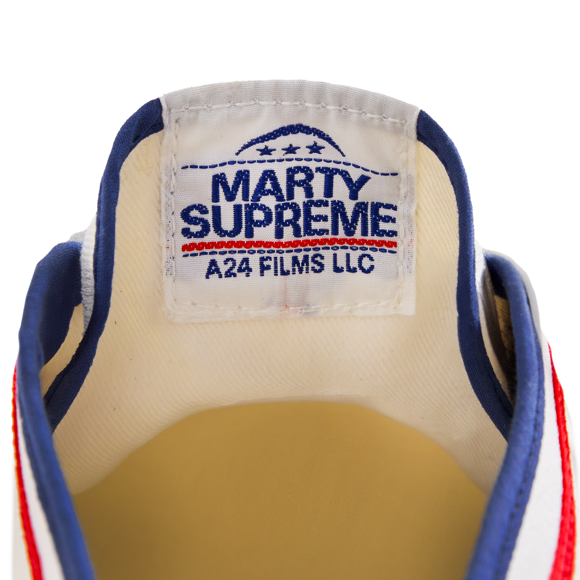 Close-up of the tongue label on the white Koyo Bear Sharpman Marty Supreme sneakers with red and blue trim, showing the A24 Films LLC logo and Made in Japan branding.