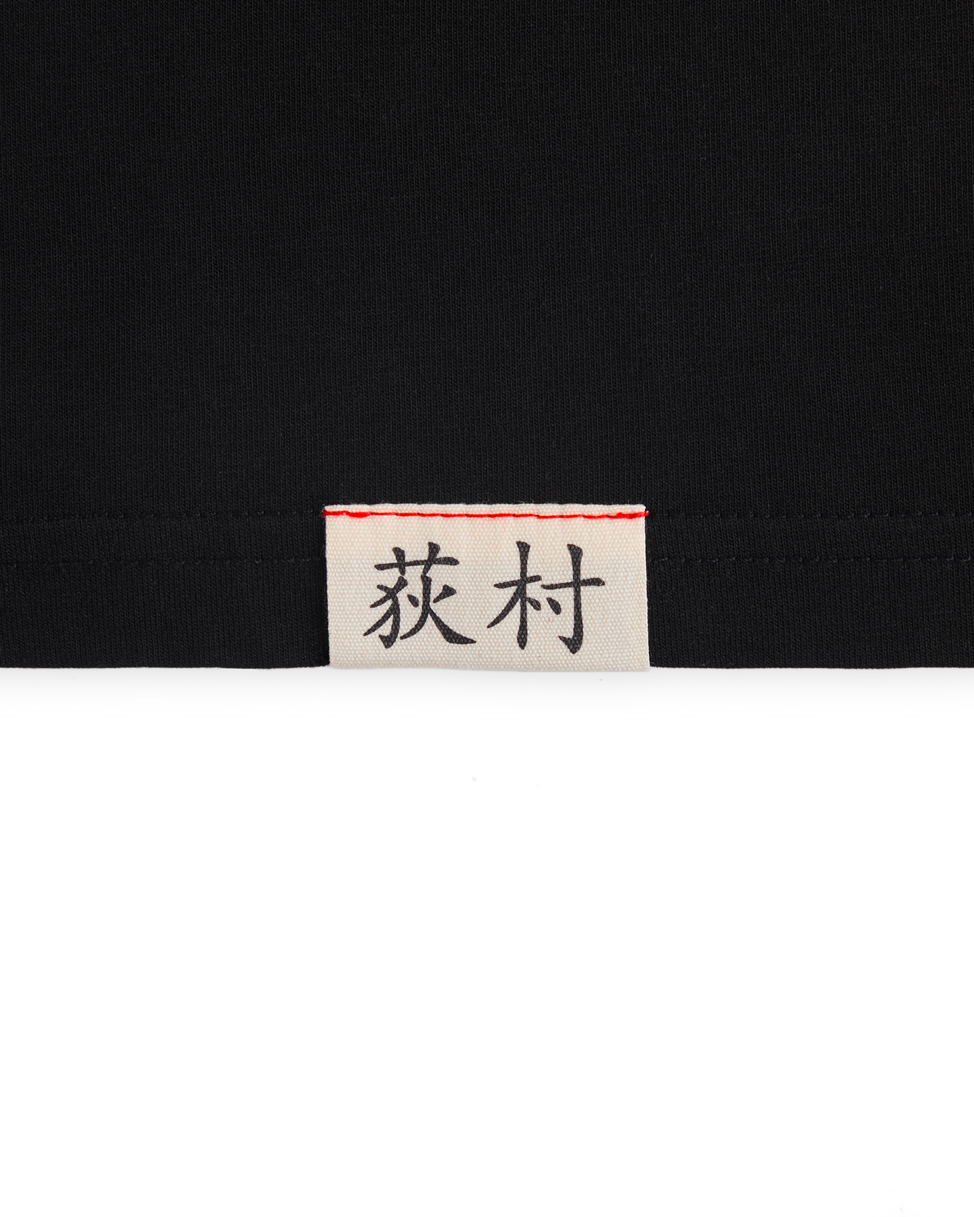 Close-up of the woven Ichiro Ogimura name label on the Koyo Bear OGI Signature Return T-shirt.