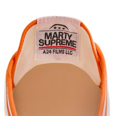 Close-up of the tongue label on the orange version Koyo Bear Sharpman Marty Supreme sneakers with red and blue trim, showing the A24 Films LLC logo and Made in Japan branding.