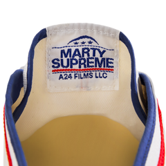 Close-up of the tongue label on the white Koyo Bear Sharpman Marty Supreme sneakers with red and blue trim, showing the A24 Films LLC logo and Made in Japan branding.