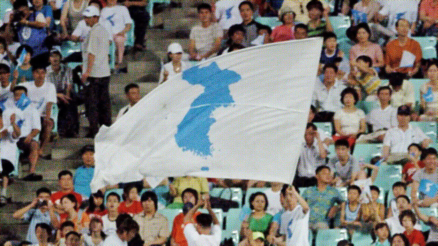 Spectators holding the unified Korea flag at an international table tennis event, symbolizing North and South Korea competing together under one banner.